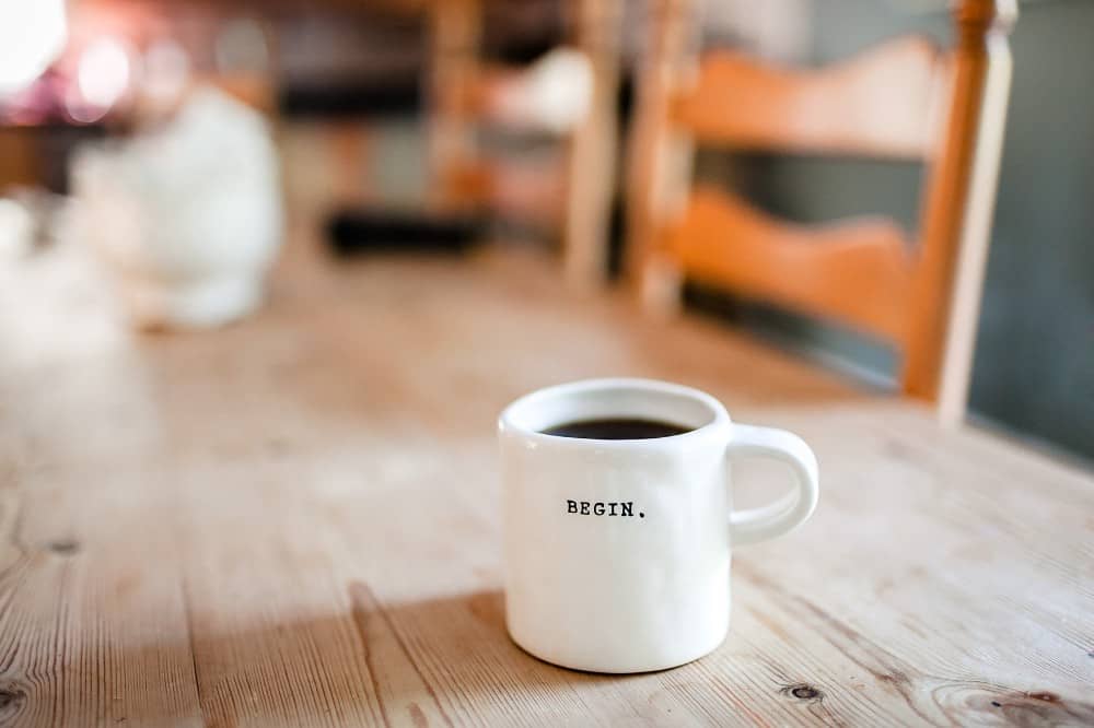 hand-formed white coffee mug with word begin in all caps
