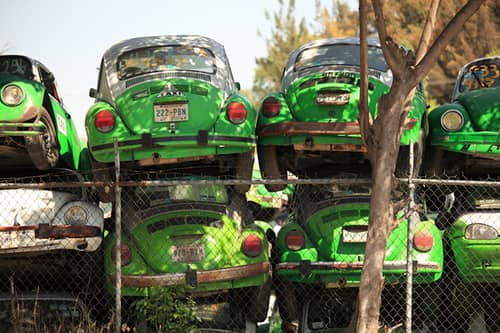 green volkswagen beatle cars in junkyard