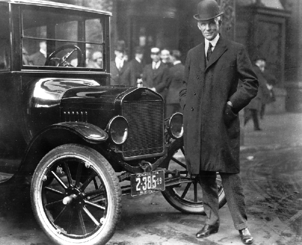 Henry Ford standing by a Ford